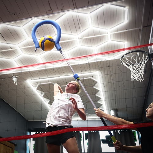 Volleyball athlete performing an attacking drill on an indoor training court at BAM BAM Training